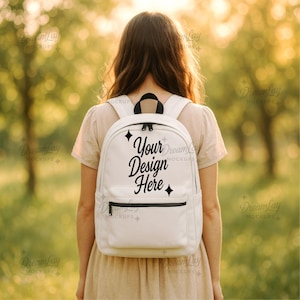 Puede incluir: Una mochila blanca con cremallera negra y bolsillo delantero. El texto "Your Design Here" está impreso en la parte delantera de la mochila en una fuente de escritura. La persona lleva un vestido beige.
