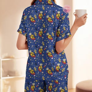 Peut inclure: Ensemble de pyjama bleu avec un motif r&eacute;p&eacute;t&eacute; d'un personnage en imperm&eacute;able jaune, d'&eacute;toiles et d'araign&eacute;es. Le haut &agrave; manches courtes et le pantalon sont en tissu doux. Le pyjama a une bordure noire.