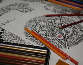 May include: A collection of adult coloring pages with intricate black and white designs, featuring geometric and floral patterns. Colored pencils in a metal tin and scattered on the pages add a pop of color. The pencils are in various shades of red, orange, and brown.