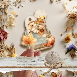 Könnte beinhalten: Ein dekoratives Büroklammer-Set mit Herbstthema, mit Kürbissen, einem Igel und einem Ahornblatt. Die Büroklammer wird von einer Hand gehalten und enthält den Text "Golden Meadow Junk Journal Hidden Paperclip". Ein kleiner Kreis zeigt "6 Piece Set + extras."