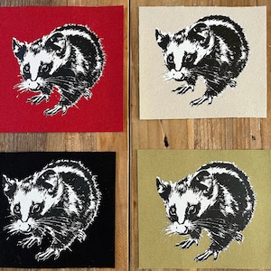 Puede incluir: Cuatro parches cuadrados con una ilustración de zarigüeya en blanco y negro. Cada zarigüeya está representada con un estilo artístico detallado. Los fondos son rojo, beige, negro y verde oliva. Los parches son probablemente para coser o manualidades.