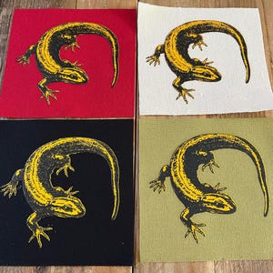 Puede incluir: Cuatro parches cuadrados de tela con un diseño de lagarto amarillo y negro. Los fondos son rojo, blanco, negro y verde oliva. El lagarto está enroscado con la cola tocando su espalda. Adecuado para coser o manualidades.