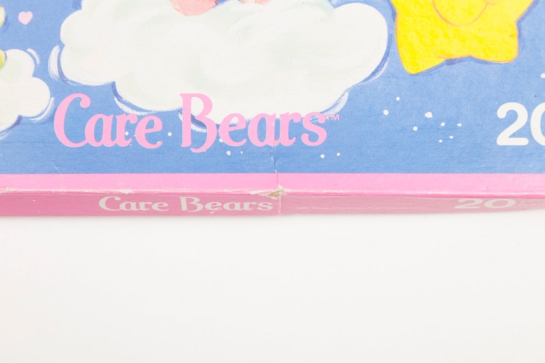 Może przedstawiać: R&oacute;żowy i niebieski kalendarz Care Bears z tekstem "Care Bears" i "20" na przodzie.