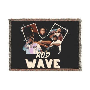 May include: Black woven throw blanket featuring multiple images of a musician, with the text "ROD WAVE" in cream-coloured block letters. The blanket has a fringed edge in shades of brown and tan.