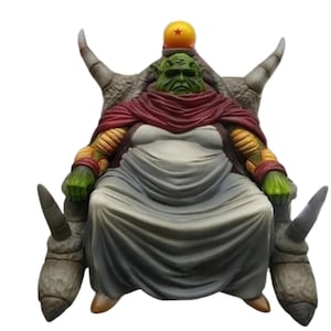 May include: A detailed figurine of a green-skinned character seated on a throne. The figure wears a red cape and a white robe. The throne has large, curved horns and a yellow sphere with a star on top.