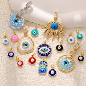 May include: An assortment of gold and silver-coloured pendants and charms, all featuring the evil eye motif. The charms are in shades of blue, white, pink, red, and black, with detailed designs and sparkling embellishments. The pendants come in various shapes.