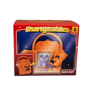 May include: A red box with the word "Changeables" in yellow. Inside is an orange Boo Bot toy with a pumpkin-shaped head and a purple creature inside. The box also shows a pumpkin bucket and a jack-o'-lantern.