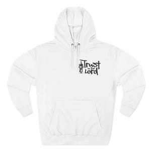 May include: White hoodie with a front pocket and drawstring hood. The hoodie features a black graphic of a figure and the words "Trust in the Lord" on the front. A casual, comfortable garment.