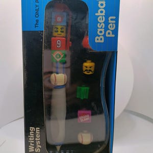 May include: A blue box containing a "Baseball Pen" writing system. The pen is white and gray with baseball-themed details. Includes Lego-style accessories and the text "You Connect & Build!" and "GRAND SLAM!"