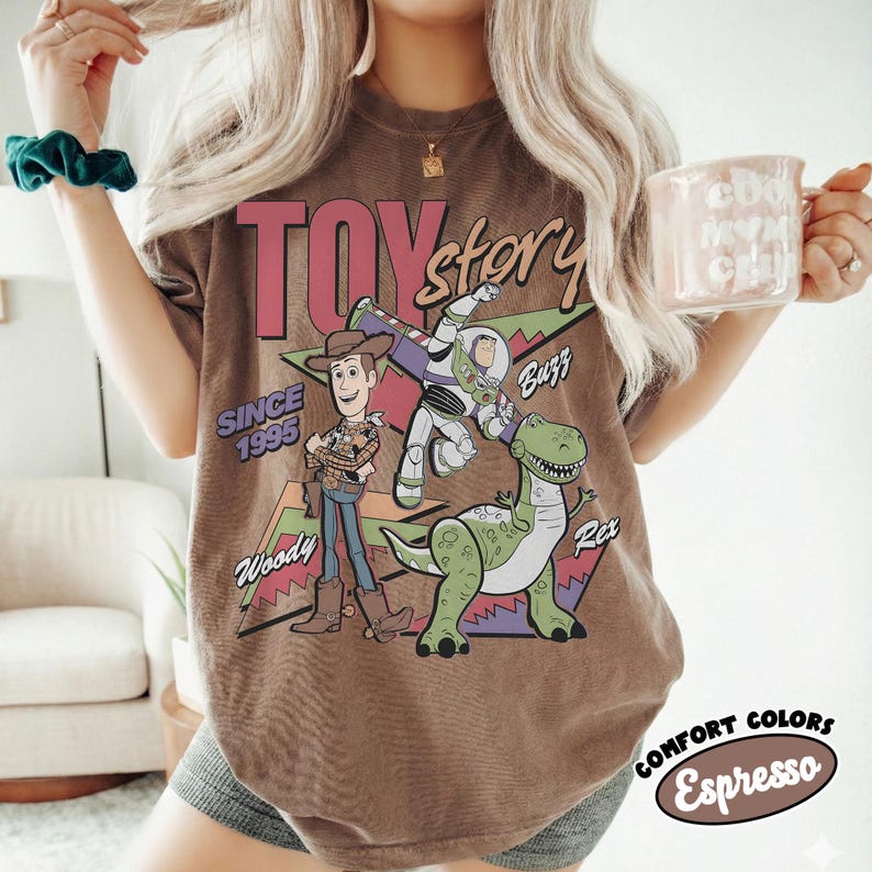 May include: A white ceramic mug with a black handle and the text "But First, Coffee" in a bold, black font. The mug is set against a blurred background, suggesting a cosy setting.