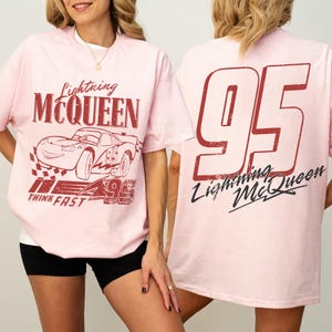 May include: Pale pink t-shirt with Lightning McQueen graphics. The front shows the character's name and image, plus the number 95 and the words "Think Fast." The back of the shirt has a large "95" and the character's name.