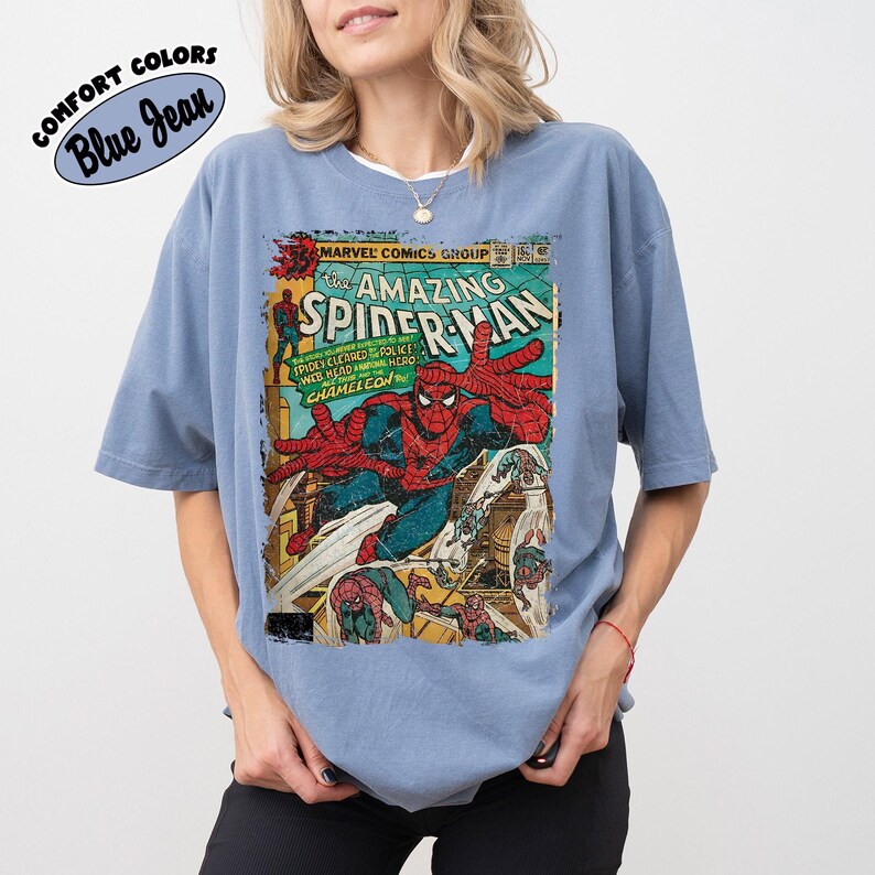 May include: Blue jean colored t-shirt featuring a vintage comic book cover of The Amazing Spider-Man. The comic book cover has a distressed look with Spider-Man in action, with the text "MARVEL COMICS GROUP" and "SPIDER-MAN".