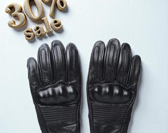 May include: A pair of black leather gloves with perforated details and padded knuckles. The gloves are displayed on a light blue background with the text "30% sale" in gold lettering.
