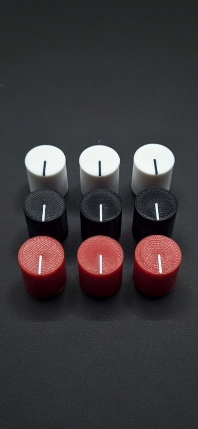 Puede incluir: Nueve perillas de control cil&iacute;ndricas en blanco, negro y rojo. Cada perilla tiene un indicador de l&iacute;nea vertical blanca. Las perillas est&aacute;n dispuestas en una cuadr&iacute;cula de 3x3 sobre un fondo oscuro.