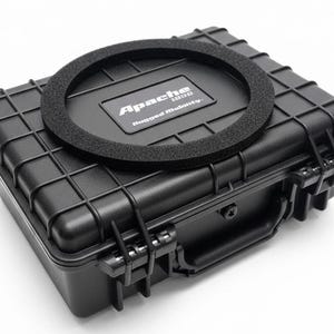 Peut inclure: Une mallette noire rectangulaire Apache 1800 Rugged Mobility avec une surface texturée et un anneau en mousse noir sur le dessus. La mallette a une poignée et des loquets sécurisés.