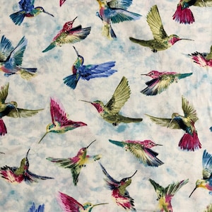 May include: A fabric pattern featuring numerous hummingbirds in flight. The birds display a variety of colors, including green, pink, blue, and yellow, set against a light blue and white background. The design is a repeating pattern.