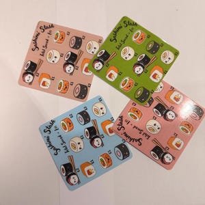 May include: Four square coasters with sushi illustrations in pink, green, blue, and coral. Each coaster features various sushi rolls, chopsticks, and the text "Sashimi Stash". The coasters are designed for a fun, food-themed aesthetic.