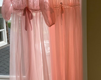 Op de afbeelding: Twee roze, doorschijnende nachtjassen hangen aan houten hangers. De nachtjason aan de linkerkant heeft kantdetails en een strik in de taille. De nachtjason aan de rechterkant is mouwloos en heeft kantversiering.