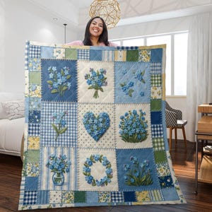Könnte beinhalten: Ein Patchwork-Quilt mit gestickten blauen Vergissmeinnicht auf hellblauem und weißem Hintergrund. Der Quilt hat eine Vielzahl von Mustern, darunter Vichy, Streifen und Blumendesigns. Der Quilt hat eine quadratische Form.
