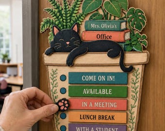 Puede incluir: Un letrero de madera para puerta con forma de maceta y un gato negro descansando encima. Detrás del gato hay plantas verdes y libros etiquetados como Mrs. Olivia's Office. Debajo hay seis barras de estado: COME ON IN!, AVAILABLE, IN A MEETING, LUNCH BREAK, WITH A STUDENT, DO NOT DISTURB.