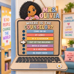 Peut inclure: Une enseigne murale en bois en forme d'ordinateur portable avec un personnage aux cheveux bouclés et le texte MRS. OLIVIA. L'écran affiche WHERE IS THE COUNSELOR? avec une liste d'options de statut comme COME ON IN et OUT OF THE BUILDING.
