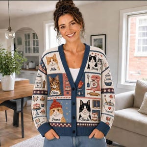 May include: A V-neck button-down cardigan featuring a patchwork design with illustrations of cats named Milo, Daisy, Oliver, Peanut, and Charlie, alongside kitchen items like a flour jar, sugar jar, mixer, and rolling pin on a cream and blue background.