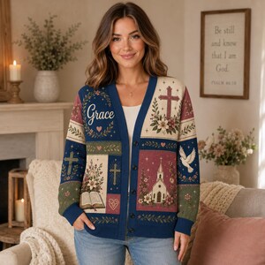 May include: A navy blue button-down cardigan featuring a patchwork design with religious motifs including a church, a dove, crosses, an open book, and the word Grace in script. The pattern includes floral accents and heart shapes in muted tones.