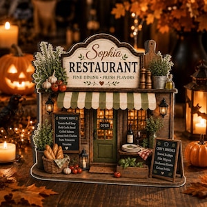 May include: A wooden miniature restaurant facade labelled Sophia Restaurant Fine Dining Fresh Flavors with a green striped awning, a menu board listing soups and entrees, a basket of bread, a wine bottle, and a Chef's Specials sign on a stand.