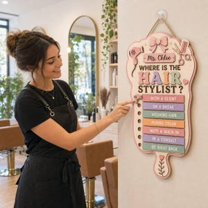 May include: A wooden wall sign with a light wood finish featuring the text Ms. Chloe WHERE IS THE HAIR STYLIST? and a sliding indicator. It includes pastel-colored labels for status updates like WITH A CLIENT, ON A BREAK, and WASHING HAIR.