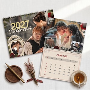 May include: A 2027 wall calendar featuring scenes from the television series Outlander, including images of the main characters, a January calendar page, a gold pen, a sprig of dried heather, and a ceramic teacup on a saucer.