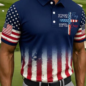 May include: Navy blue polo shirt featuring a distressed American flag design. The sleeves display the US flag, while the body has a faded red and white stripe pattern. Text on the shirt reads "Stand for the Flag, Kneel for the Cross."