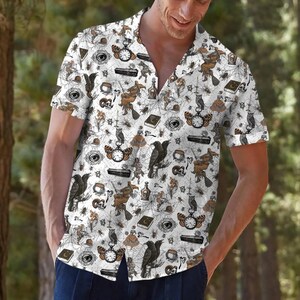 Puede incluir: Una camisa de manga corta con botones en color blanco que presenta un estampado integral de ilustraciones en negro y marrón, incluyendo brujas en escobas, cuervos, búhos, arañas, telarañas, ataúdes, relojes de bolsillo, calaveras y frascos.