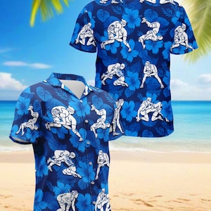 Könnte beinhalten: Blaues Hawaiihemd mit einem Muster aus weißen Wrestling-Figuren und blauen Blumendesigns. Das Hemd hat kurze Ärmel und eine Knopfleiste. Der Hintergrund zeigt eine Strandszene mit Palmen und blauem Himmel.