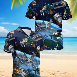 Puede incluir: Una camisa de manga corta con un diseño temático espacial. La tela azul oscuro de la camisa está cubierta con imágenes de satélites, estaciones espaciales y la Tierra desde el espacio. El diseño es detallado y vibrante, creando un aspecto único y llamativo.