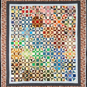 May include: A large quilt made of many different fabric squares, each with a unique pattern. The quilt is made in a patchwork style, with the squares arranged in a grid pattern. The quilt is primarily made of brown, green, blue, and white fabrics.