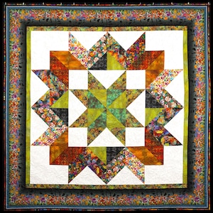 May include: A colorful quilt with a starburst pattern in shades of green, orange, and black. The quilt is framed with a floral border.