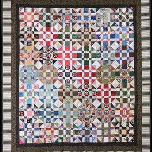 May include: A quilt with a patchwork design featuring a variety of colorful fabrics. The quilt is made up of squares and triangles, and the colors are bright and cheerful. The quilt is framed with a black and white striped border.