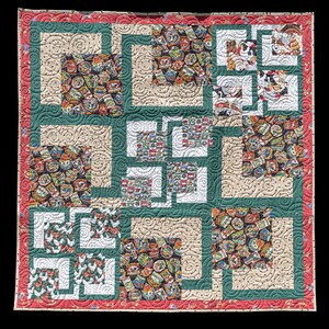 May include: A handmade quilt with a patchwork design. The quilt features squares of patterned fabric in various colors, including red, green, beige, and white. The squares are framed by green and beige borders, with a red border around the edge.