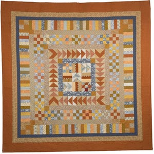May include: A square patchwork quilt featuring a central block of assorted patterned squares surrounded by concentric borders of flying geese triangles, small checkered squares, and vertical fabric strips in shades of rust, blue, and tan.
