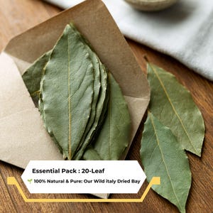 Könnte beinhalten: Eine Ansammlung getrockneter Lorbeerblätter, von denen einige in einem braunen Papierumschlag stecken und zwei daneben liegen. Der Text auf der Einblendung lautet: Essential Pack : 20-Leaf, 100% Natural & Pure: Our Wild italy Dried Bay. Die Blätter sind grün.