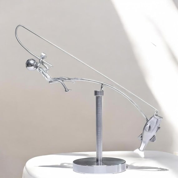 A charming hand-crafted fisherman balancing sculpture where the whole piece defies gravity with a fishing line counterweight — genuinely conversation-starting desk or shelf art.