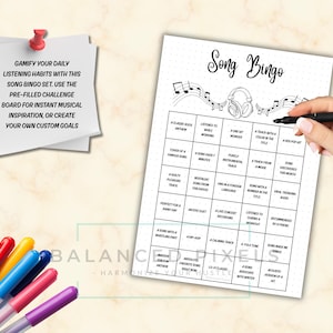 May include: A black and white Song Bingo game sheet with musical notes and headphones. The sheet has a grid of prompts and the text "Song Bingo" at the top. A hand holds a black pen over the sheet. Colorful pens are in the lower left.