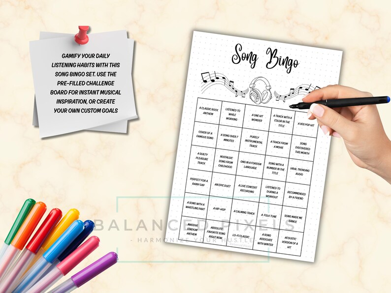 May include: A black and white Song Bingo game sheet with musical notes and headphones. The sheet has a grid of prompts and the text "Song Bingo" at the top. A hand holds a black pen over the sheet. Colorful pens are in the lower left.
