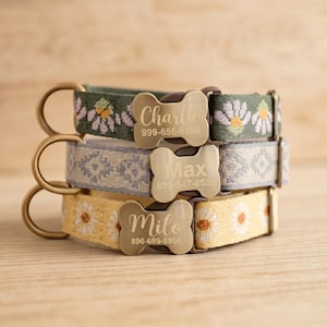 Puede incluir: Tres collares personalizados para perros apilados. El collar superior es verde con patrones de margaritas blancas y amarillas. El collar del medio es azul claro con un patrón geométrico. El collar inferior es amarillo con patrones de margaritas. Cada collar tiene una placa con forma de hueso.