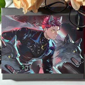 May include: A rectangular art print featuring an anime-style character with red hair and wolf ears, wearing a black jacket and a gold crescent moon necklace. The character is flanked by two snarling grey wolves with yellow eyes against a dark background.