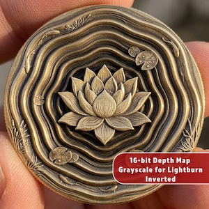 Puede incluir: Moneda de color bronce con un diseño detallado de flor de loto en el centro, rodeada de patrones concéntricos en forma de olas. La moneda presenta peces y nenúfares. El texto en la moneda dice "16-bit Depth Map Grayscale for Lightburn Inverted".
