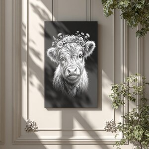 May include: Black and white art print of a Highland cow with a floral crown. The cow's portrait is detailed, with a focus on its fluffy fur and gentle expression. The artwork is displayed on a wall, adding a touch of rustic charm to the decor.