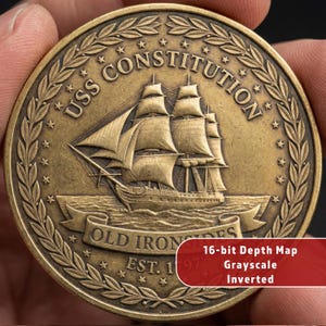 May include: A bronze coin featuring the USS Constitution sailing ship. The coin is inscribed with "USS Constitution", "Old Ironsides", and "EST. 1797". The coin is held in a hand.