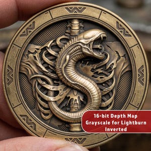 May include: A bronze-colored coin with a detailed relief of an alien creature with an open mouth, surrounded by a circular border. The coin has the text "16-bit Depth Map Grayscale for Lightburn Inverted".