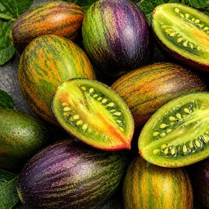 May include: A close-up of several heirloom tomatoes, some halved to reveal the interior. The tomatoes have a mix of colors, including green, yellow, orange, and purple. The cut tomatoes show a vibrant yellow interior with visible seeds.